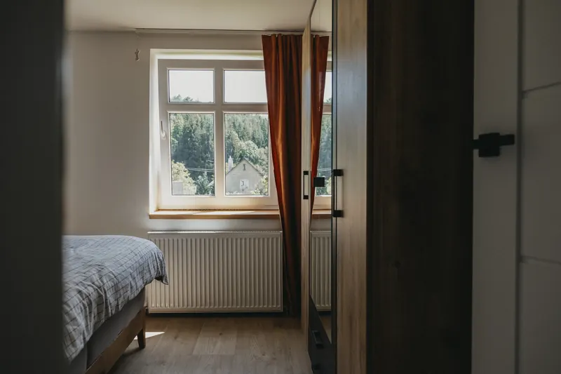 Ložnice s manželskou postelí a oknem do zeleně